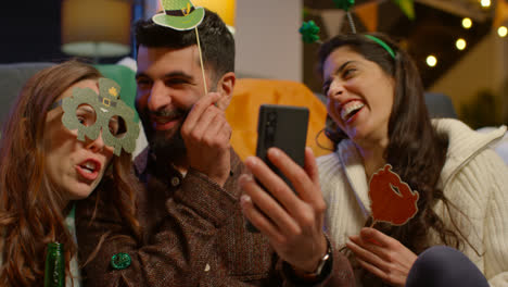 Group-Of-Friends-Dressing-Up-At-Home-Celebrating-At-St-Patrick's-Day-Party-Making-Video-Call-On-Mobile-Phone-2